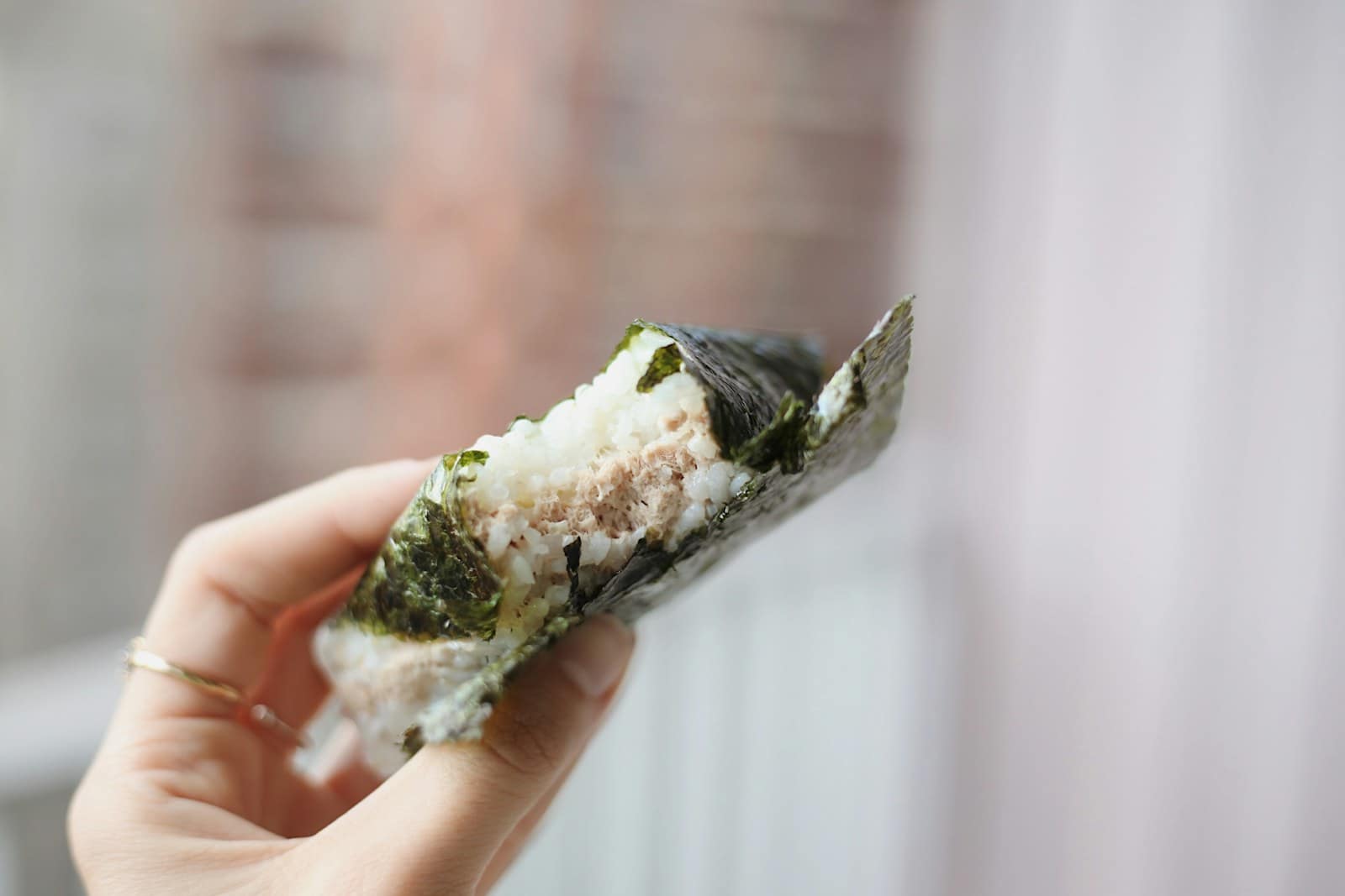 Onigiri, boulette de riz enveloppée d’algue, tenue à la main