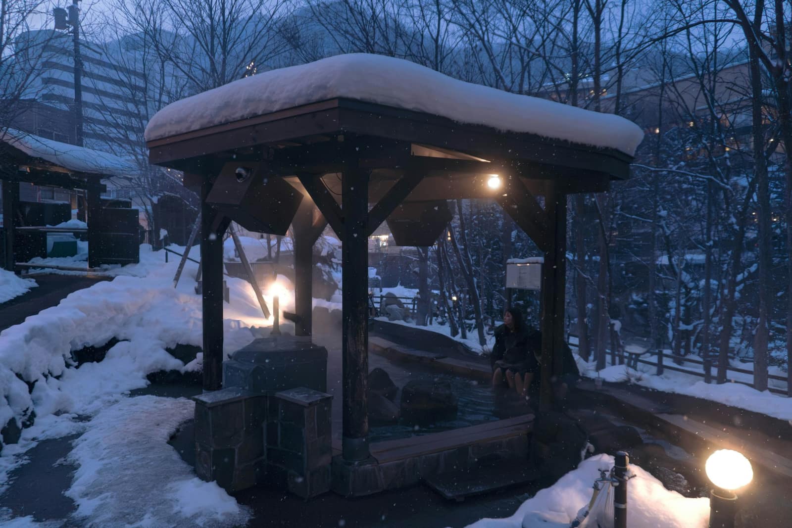Bain extérieur couvert sous la neige, éclairé à la tombée de la nuit