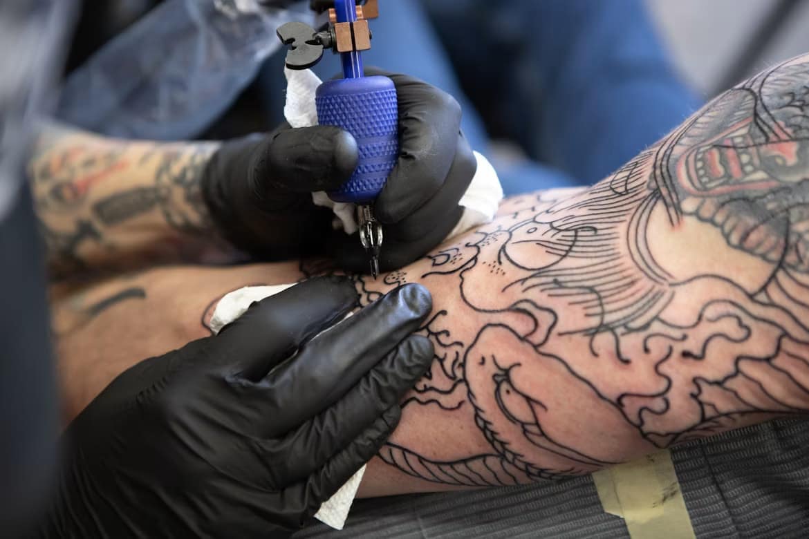 Tatoueur réalisant un motif sur le bras d'un homme